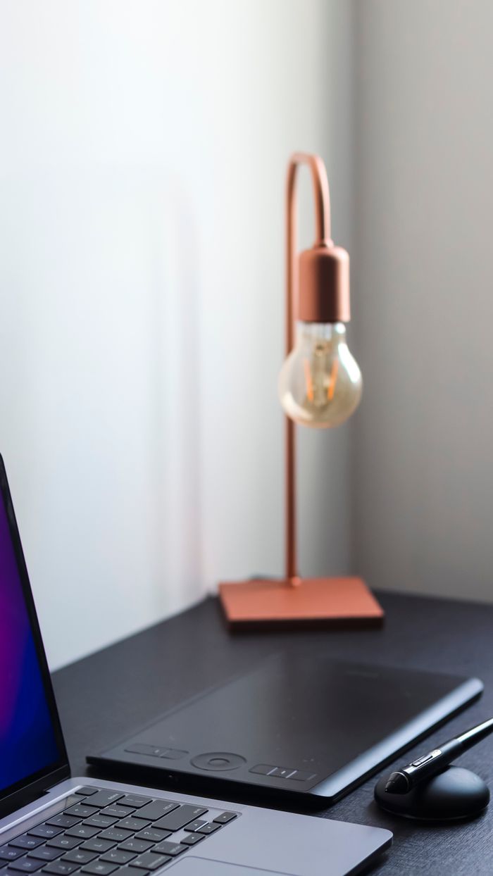 why-choose-us A sleek modern workspace featuring a laptop, digital tablet, and stylish lamp on a desk.