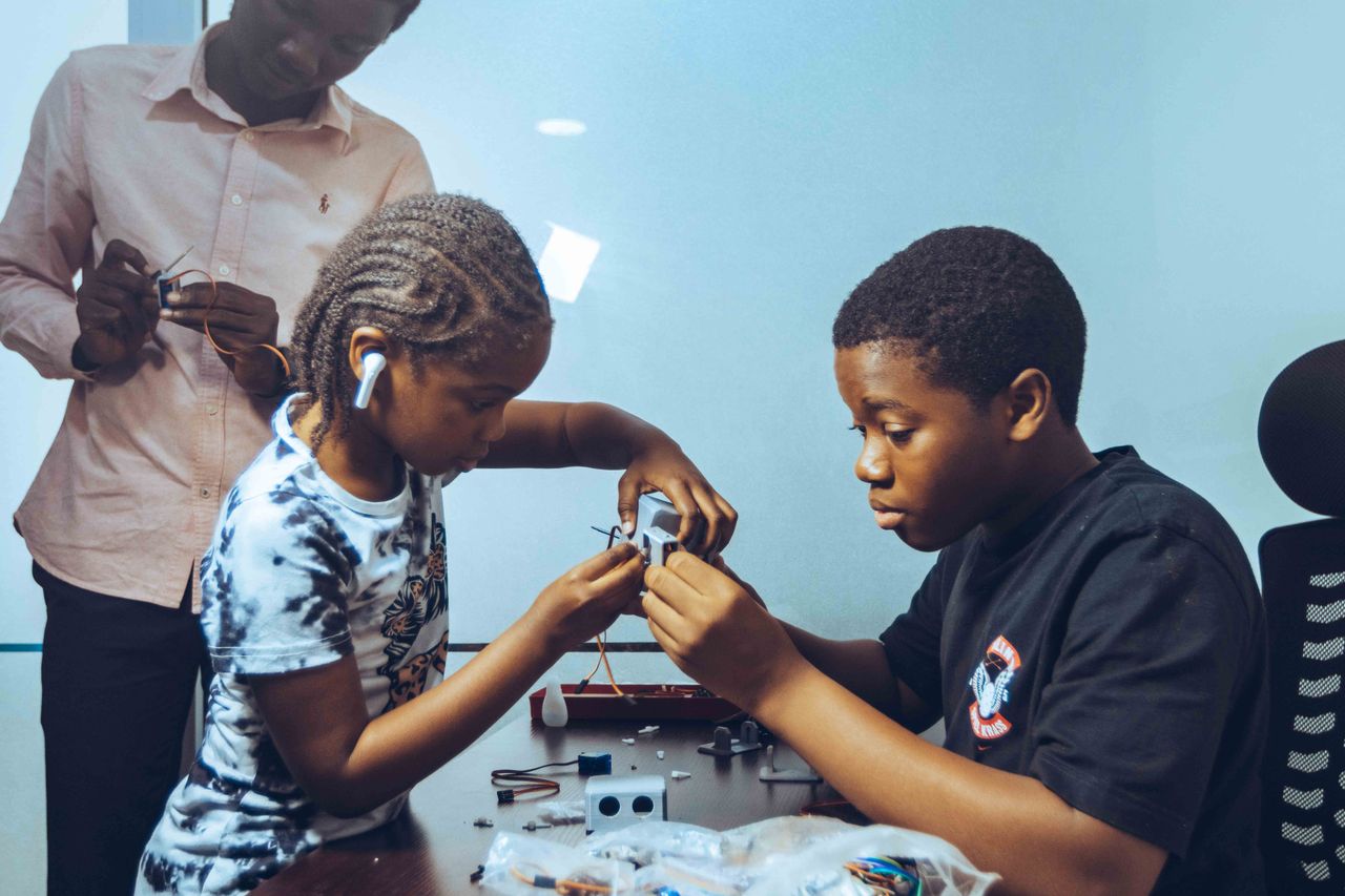 contact-img Children collaborating on electronics project in a workshop, fostering STEM education and teamwork.