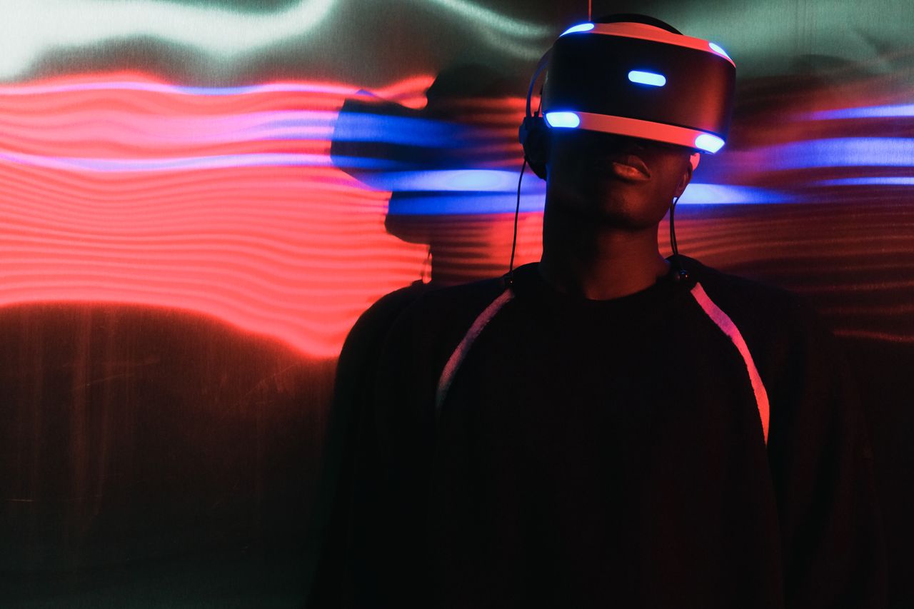 hero-img-02 A person wearing virtual reality headset surrounded by colorful neon lights, enjoying a digital world.